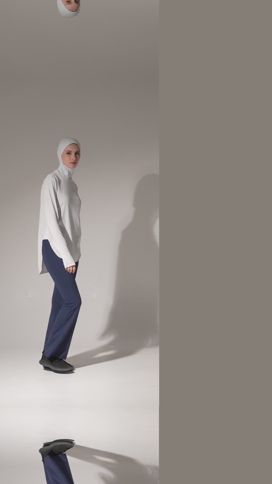 Woman in a sport hijab, white long top and navy flare leggings