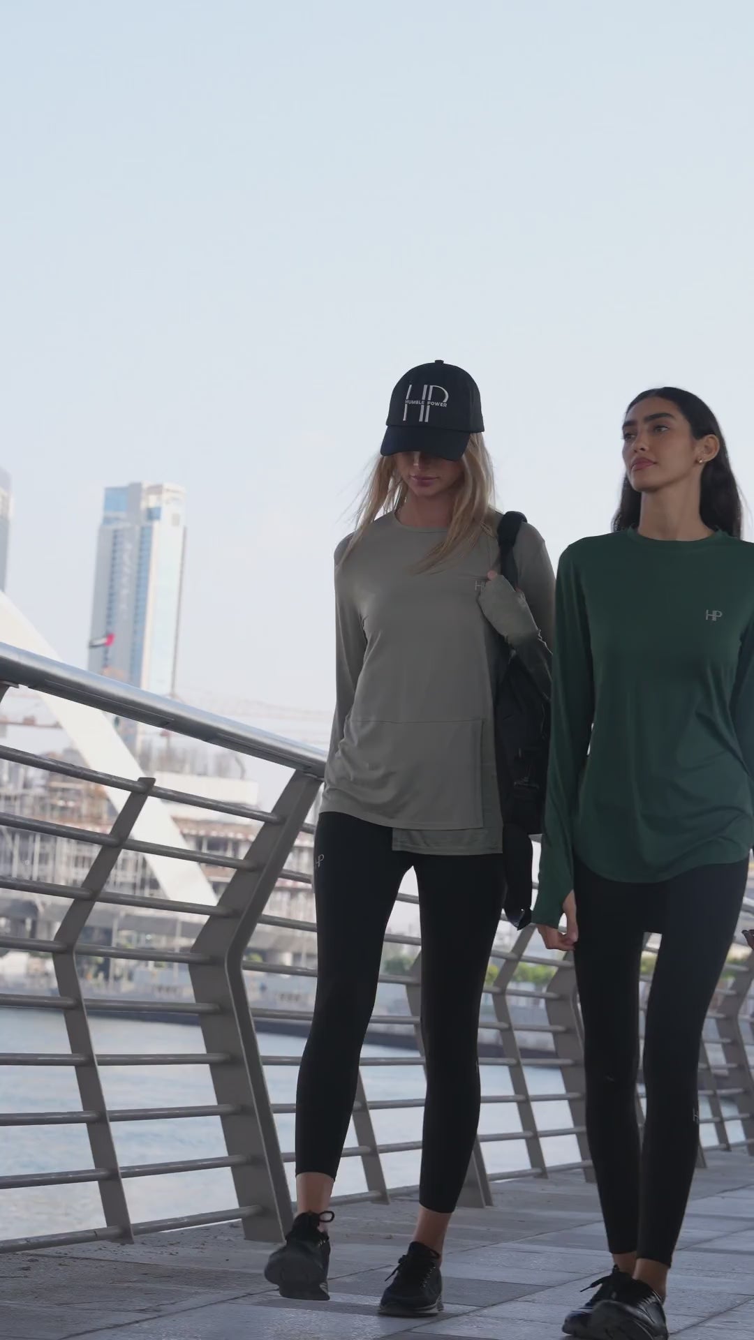 Woman in a green long modest top and leggings getting ready to run by the water in Dubai