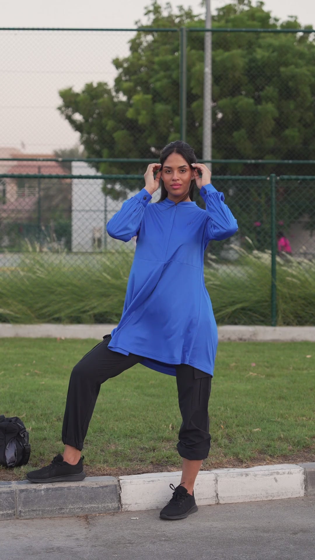 Woman running outdoors in a blue long top and black pants