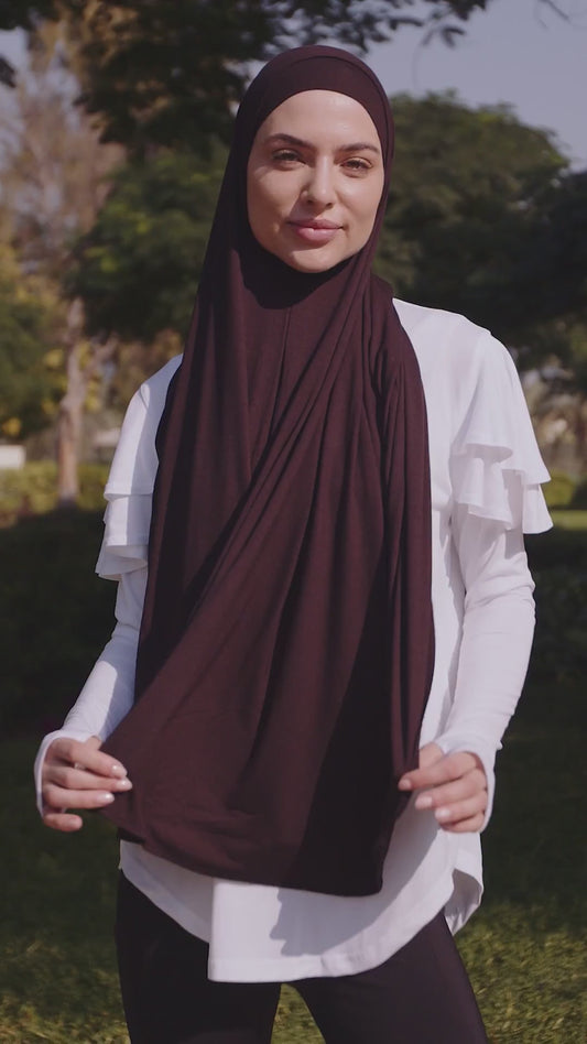 Woman in a burgundy jersey hijab and white ruffle-shoulder long top in the park