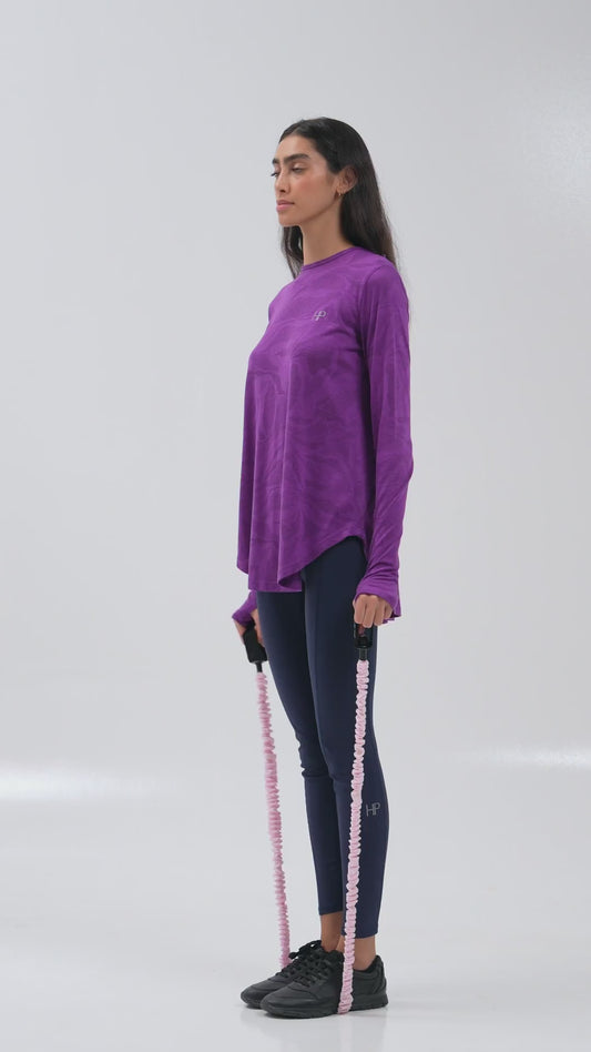Woman training with a resistance band in a purple long modest top
