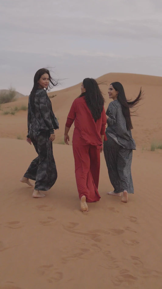 Three women in the desert at sunset wearing Siena shirt and pants sets in red, charcoal tie-dye and grey